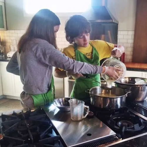 Two youth cooking students at the stove of The Kitchen at Middleground Farms