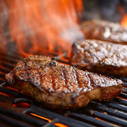 Steaks on a grill over an open flame