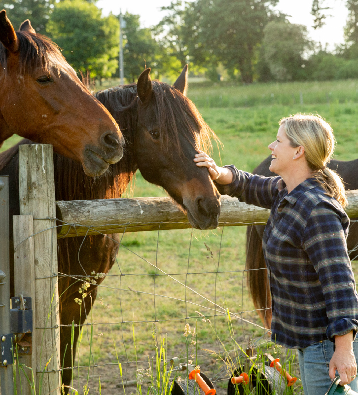 Jessica Hansen, Chef and Owner of Middleground Farms, pets one of two horses over a fence at The Kitchen at Middleground Farms