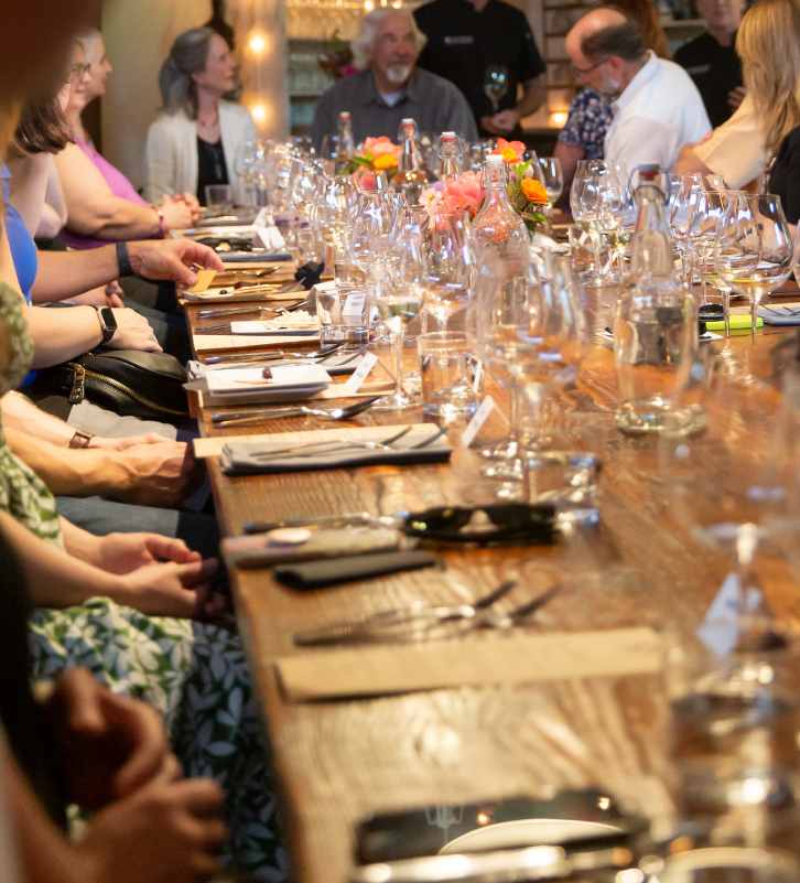 Guests sitting at the barnwood table during a private event at The Kitchen at Middleground Farms